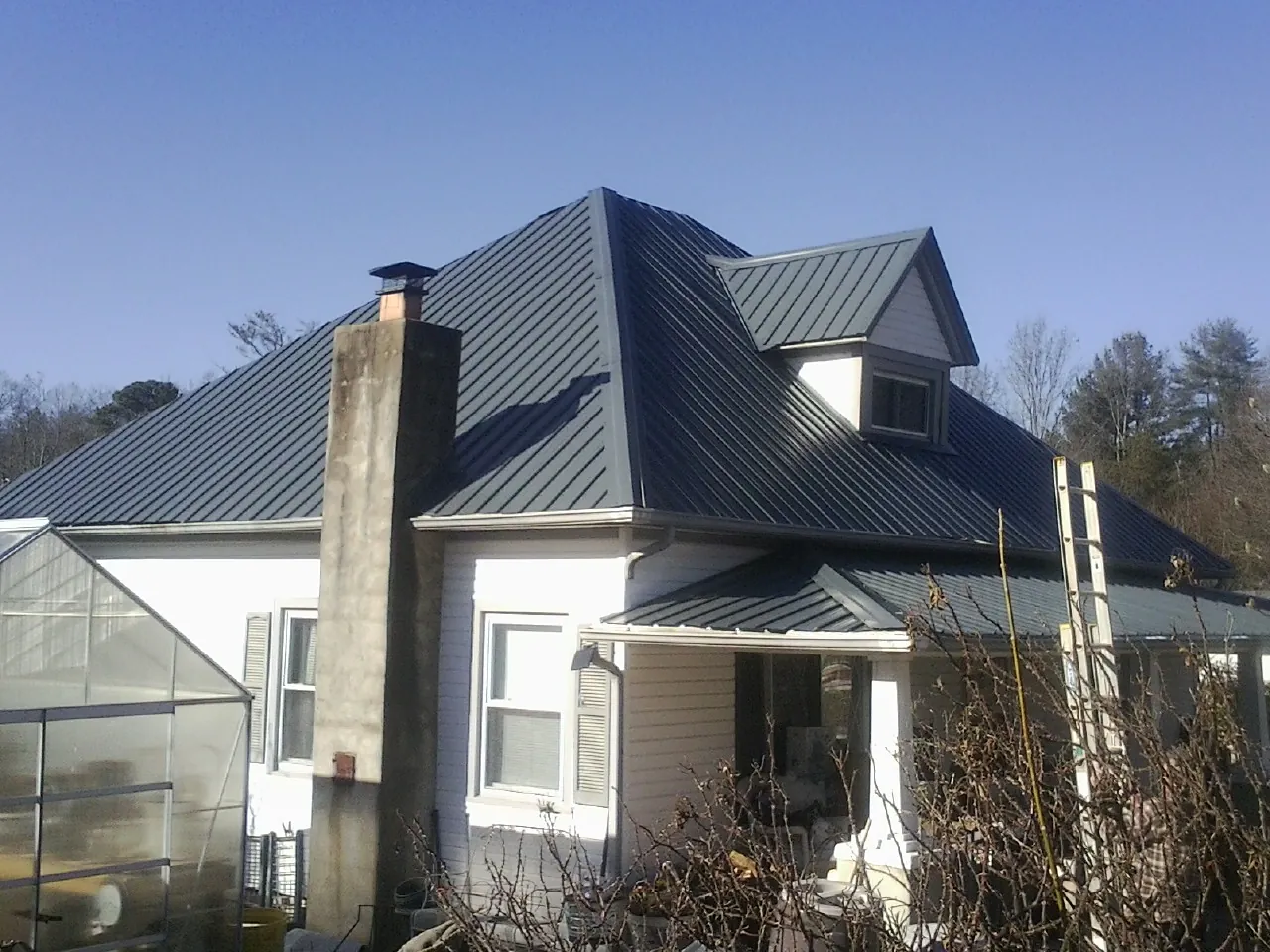 Dark blue standing seam metal roof on a white farmhouse with dormer — Slate & Tile Roof Repair by Roofing Brothers in San Juan Capistrano
