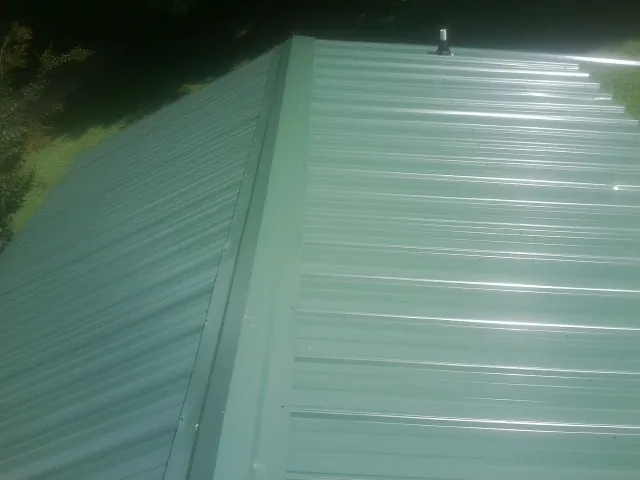 New green metal panels meeting at the ridge of a roof — Flat Roof Repair work by our crew in San Juan Capistrano