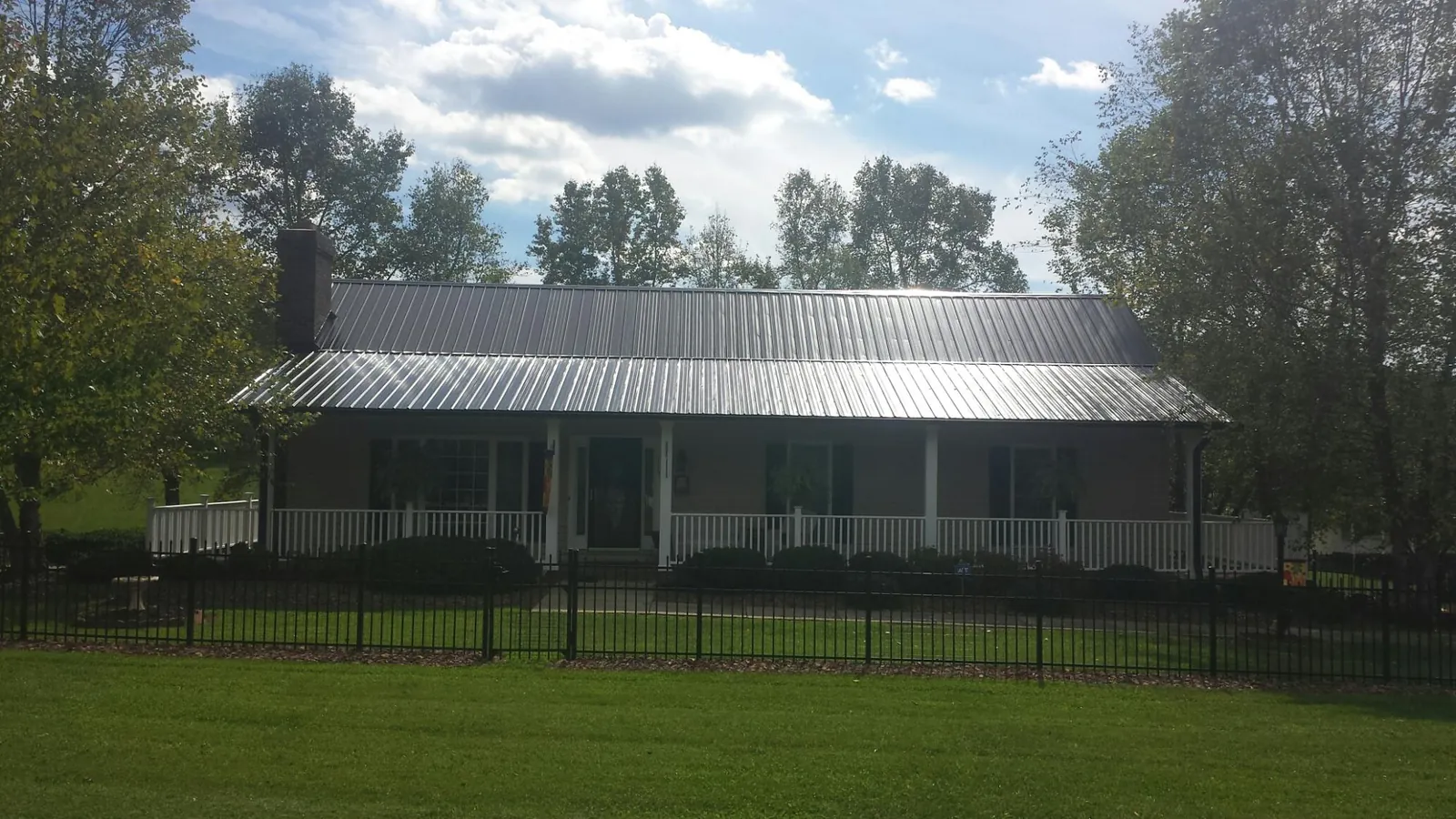 Gray metal roof on a brick ranch with a full width front porch — Gutter Guard Installation work by our crew in San Juan Capistrano