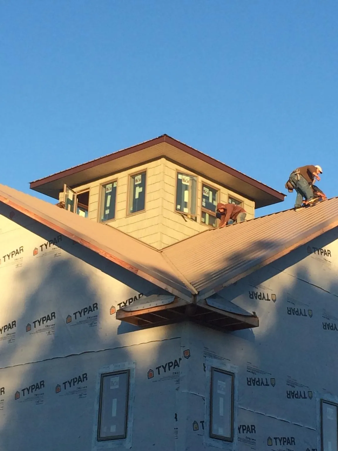 Roofers working around a rooftop cupola on a new metal roof at sunset — Roof Waterproofing in San Juan Capistrano by Roofing Brothers
